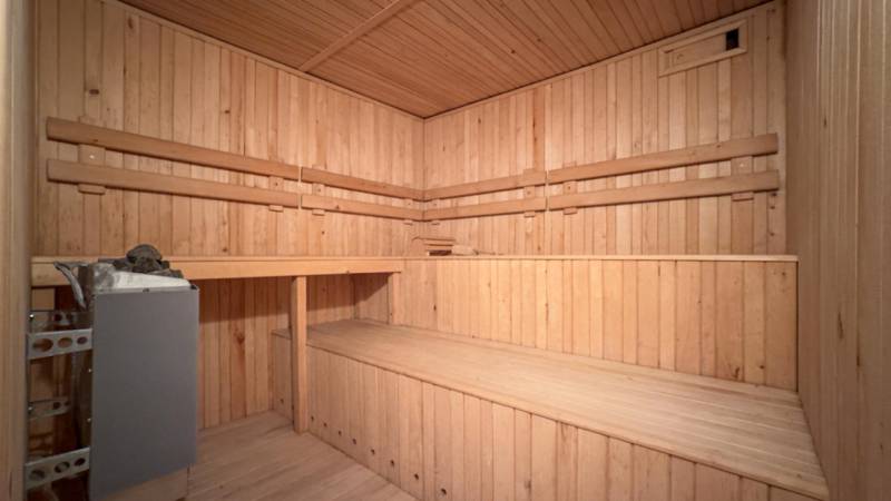 Drevená sauna v rodinnom dome, vybavená lavicami a kachľami na ohrievanie.