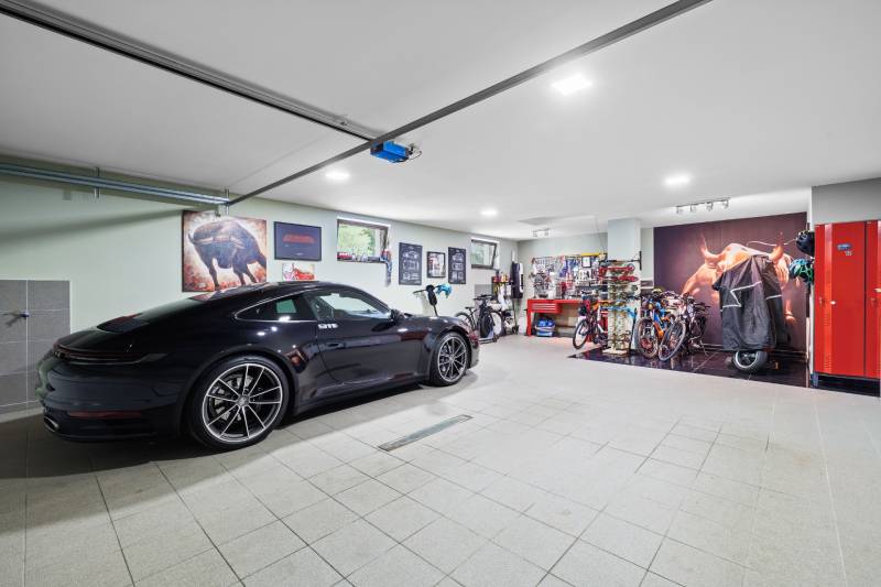Garáž v rodinnom dome s automobilom, bicyklami a zdobenými stenami s obrázkami.