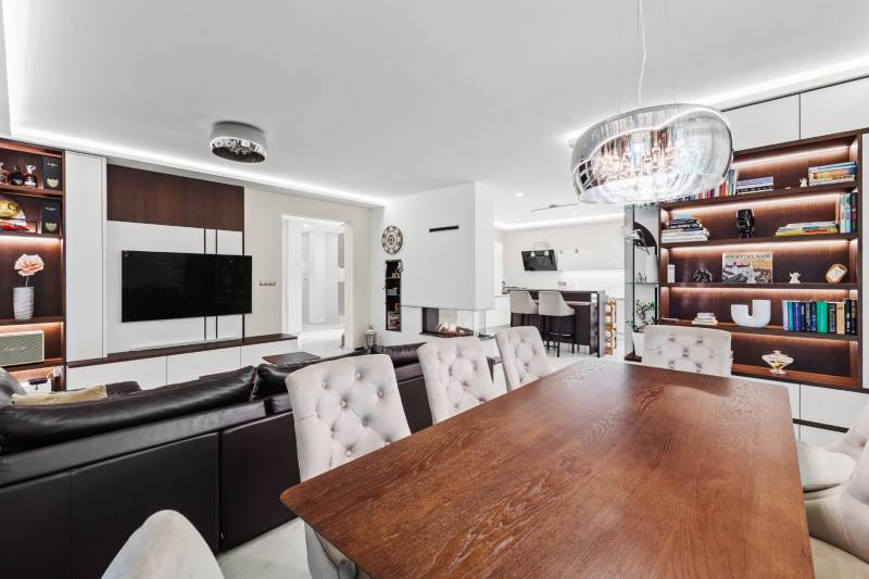 Obývacia izba s krbom, podlahou s dreveným dekorom, knižnicou a jedálenským stolom v rodinnom dome.