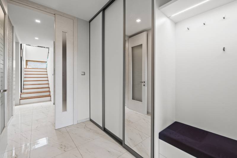 Vstupná chodba rodinného domu s dlažbou, vstavanou skriňou a schodiskom.