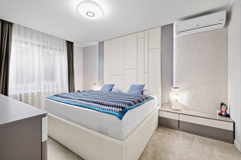 Spálňa v rodinnom dome s veľkou posteľou, klimatizáciou a dekoratívnym osvetlením.