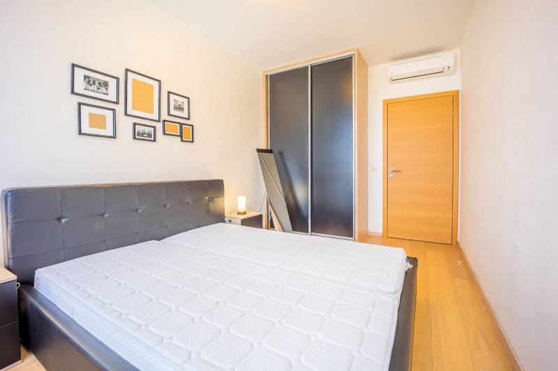 Spálňa s posteľou, skrinkami, dekorom na stene a podlahou s dreveným dekorom.