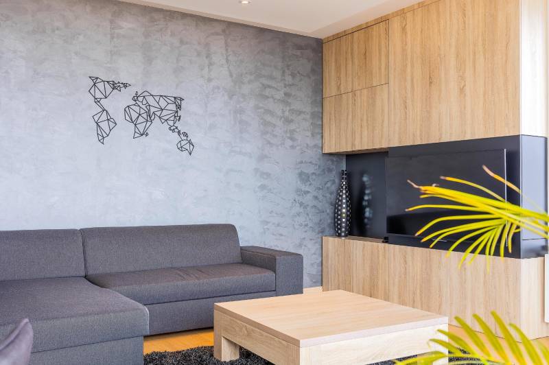 Sedačka v 3-izbovom byte s podlahou s dreveným dekorom a ozdobnou mapou sveta.