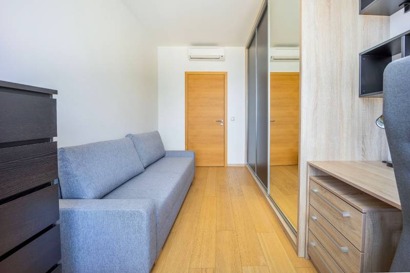 Útulná izba v 3-izbovom byte s pohovkou a podlahou s dreveným dekorom.