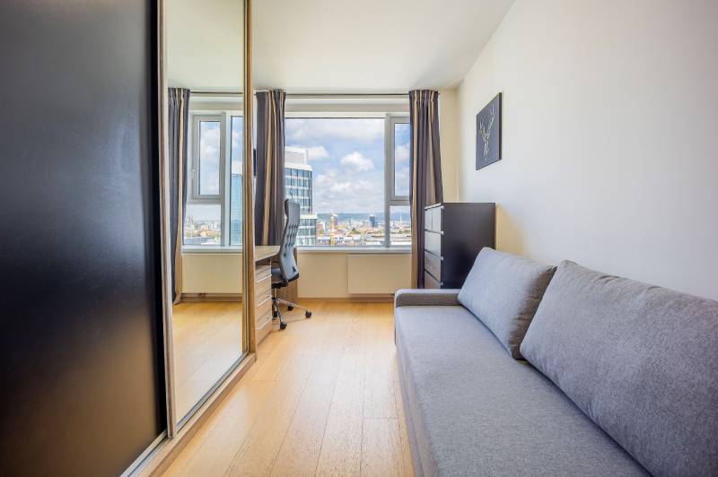 Interiér 3-izbového bytu s pohovkou, pracovným stolom a podlahou s dreveným dekorom.