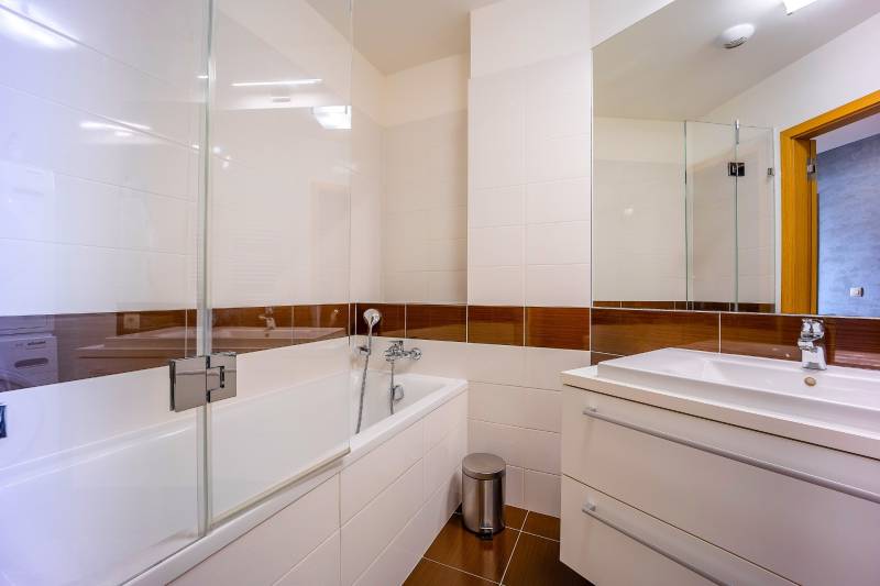 Kúpeľňa v 3-izbovom byte s vaňou a umývadlom, biele obklady na stenách.