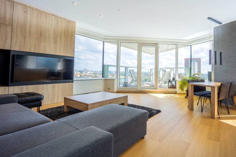 Svetlý obývací priestor v 3-izbovom byte s podlahou s dreveným dekorom a výhľadom.