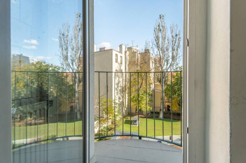 Výhľad z balkóna v 3-izbovom byte na zeleň a okolitú architektúru.