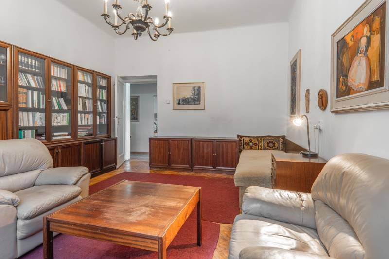 Obývacia izba s pohovkami, knižnicou a podlahou s dreveným dekorom v 3-izbovom byte.