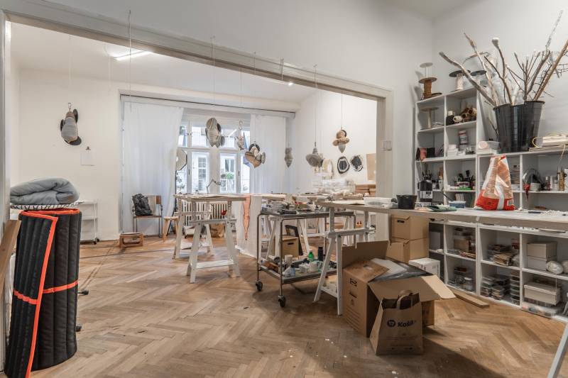 Kreatívne štúdio s nástrojmi a umeleckými projektmi v 3-izbovom byte, podlaha s dreveným dekorom.