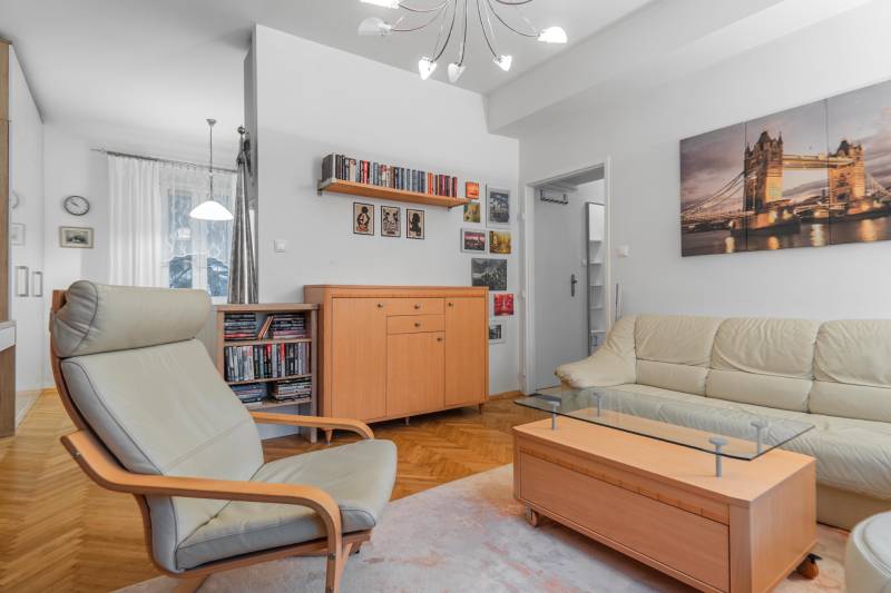 Obývačka v 2-izbovom byte s pohodlným kreslom, sedacou súpravou a podlahou s dreveným dekorom.