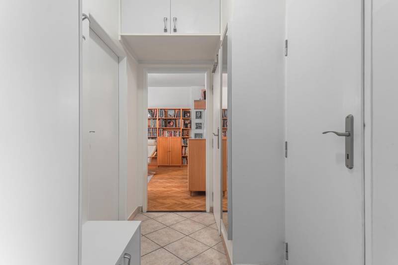 Chodba s dlaždicovou podlahou vedúca do obývačky s policami v 2-izbovom byte.