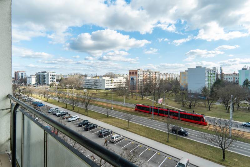 Výhľad z balkóna v Bratislave - Ružinove na ulici Súmračná s električkou a parkom.