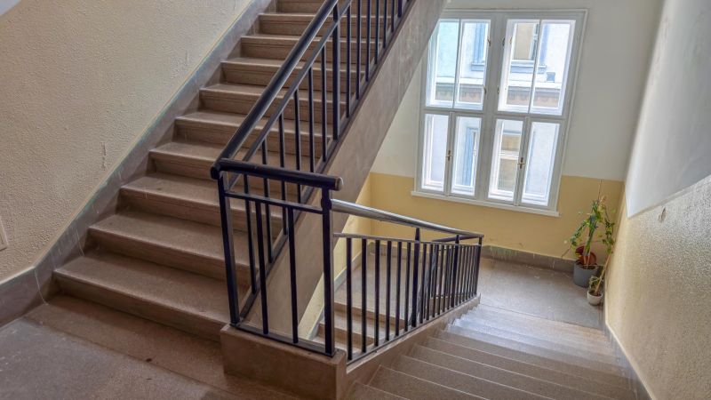 Schodisko s oknom, zábradlím a rastlinou vo vstupnej hale 3-izbového bytu.
