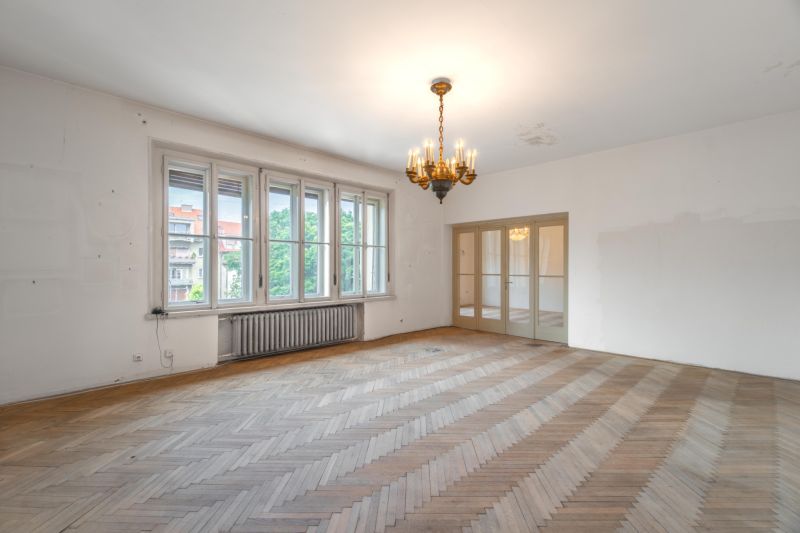 Izba s lusterom, veľké okná a podlaha s dreveným dekorom v 3-izbovom byte.
