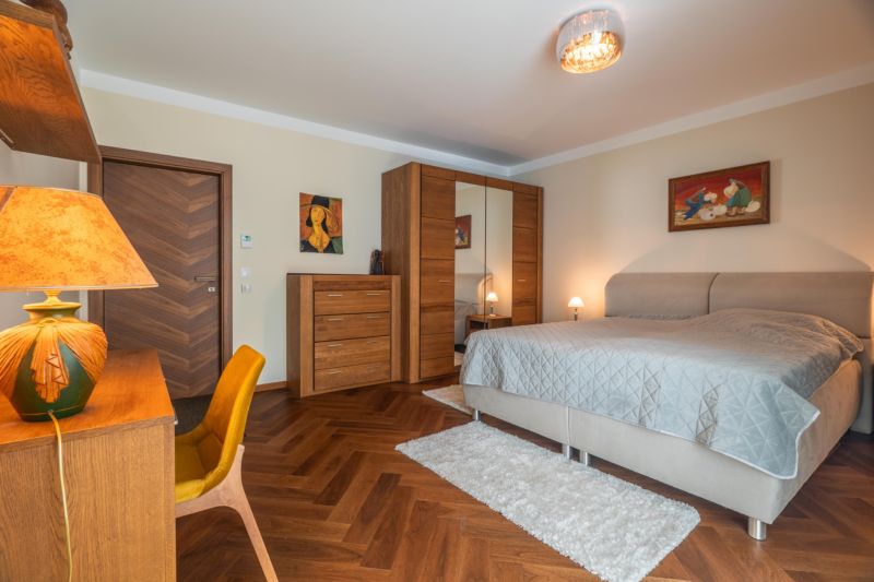 Spálňa v 3-izbovom byte s masívnym nábytkom a podlahou s dreveným dekorom.